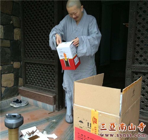 顿华法师从物资箱取出柴火炉,准备向救灾人员现场演示